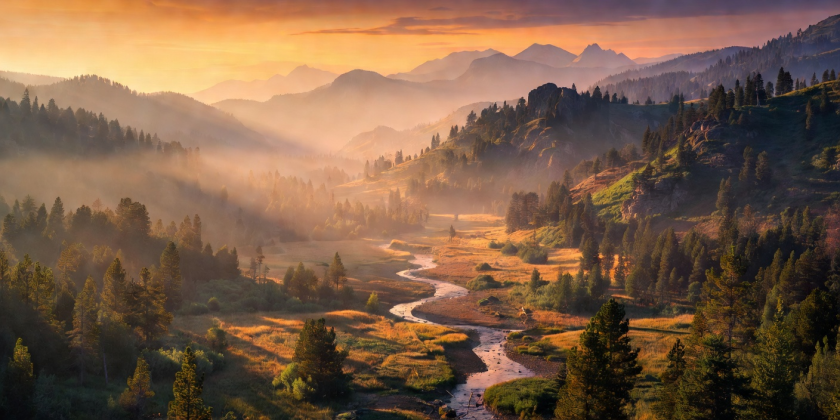 Mountain valley shrouded in warm sunset golden hour haze